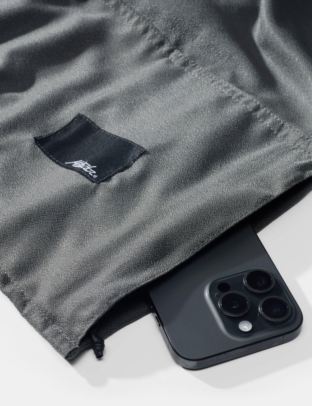 Matador NanoDry™ Packable Beach Towel - black phone on a gray fabric background