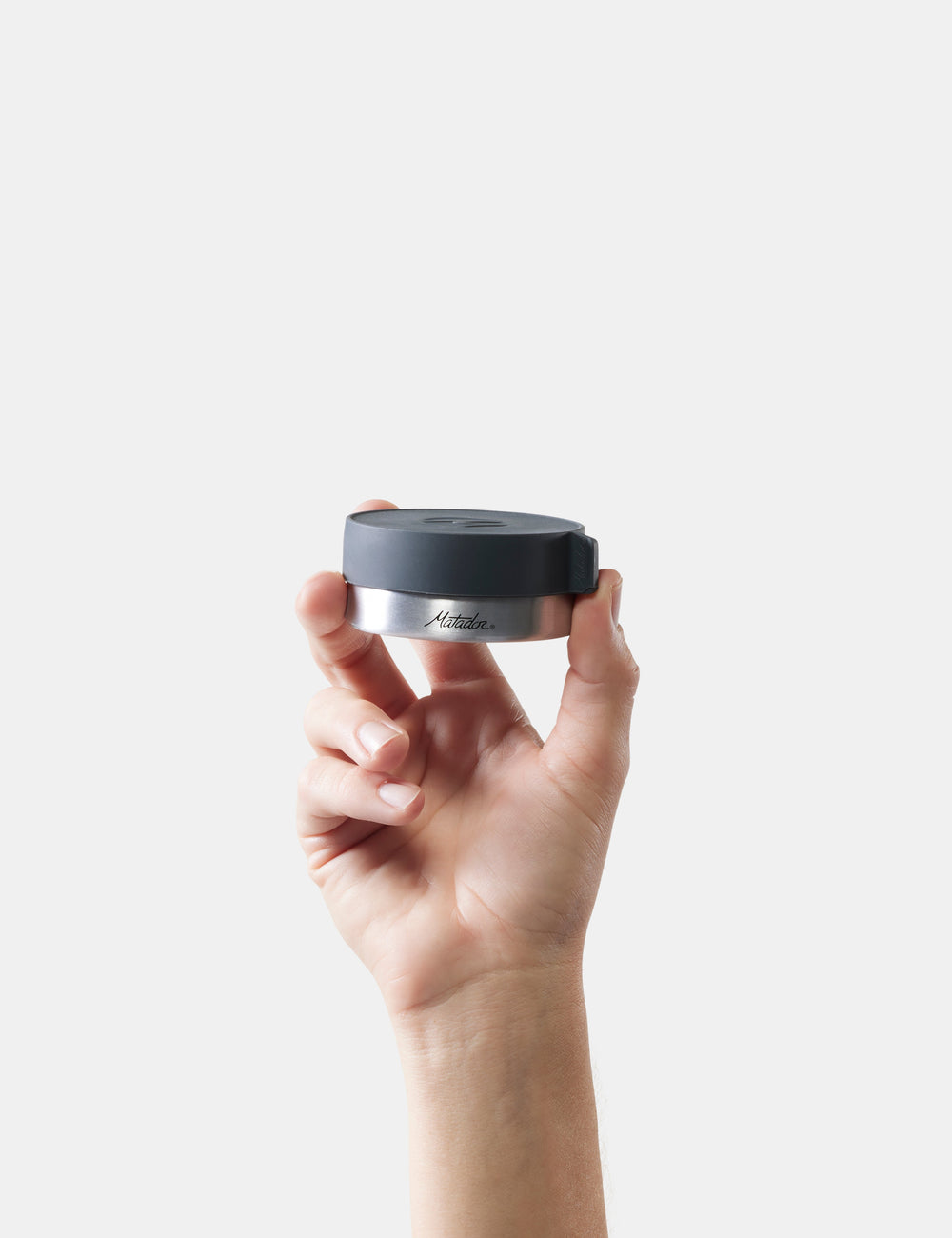 Matador Waterproof Travel Canister - 100ml - hand holding a black and silver container with 'Matador' branding against a white background
