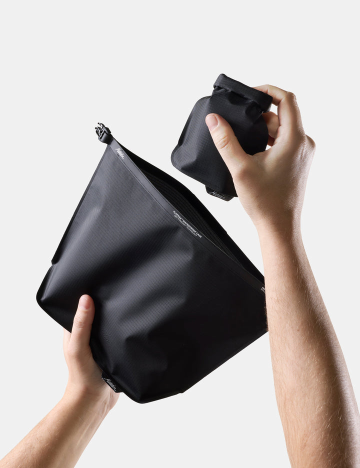 Matador FlatPak Waterproof Toiletry Case (V2) in Black - person holding a Black toiletry case with a soap bar case on a light gray background