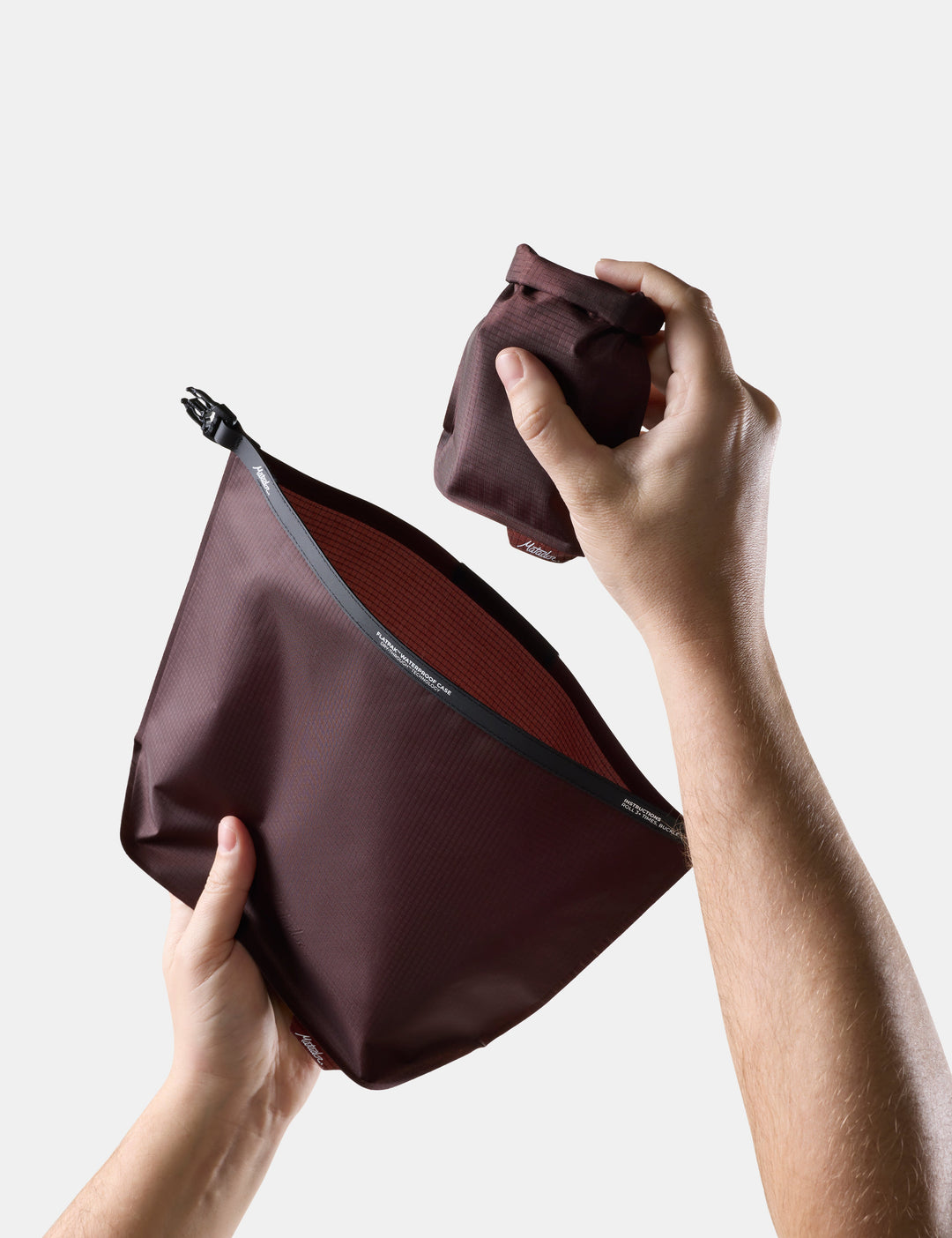 Matador FlatPak Waterproof Toiletry Case (V2) in Garnet - person holding a Garnet toiletry bag and soap bar case against a white background