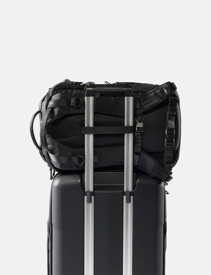 Matador 24L Adventure Pack in Black - black backpack attached to a black suitcase on a white background