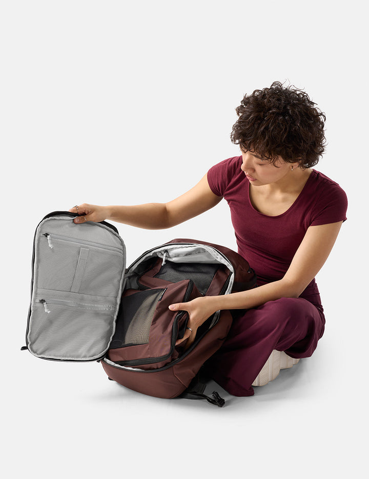 Matador 24L Adventure Pack in Garnet - person opening a large backpack on a white background