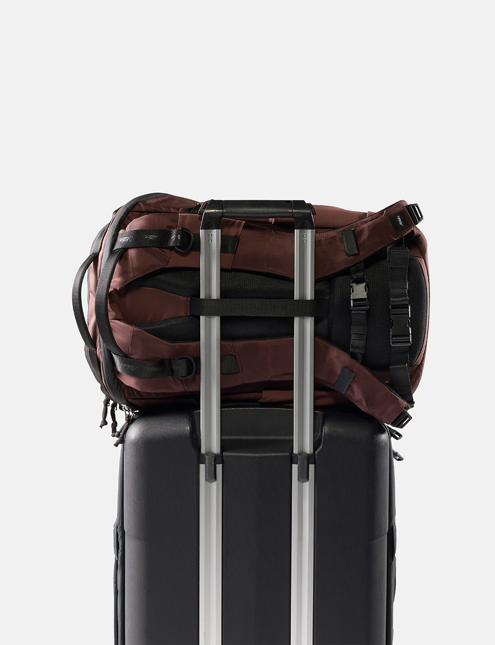 Matador 24L Adventure Pack in Garnet - garnet backpack sitting on black suitcase