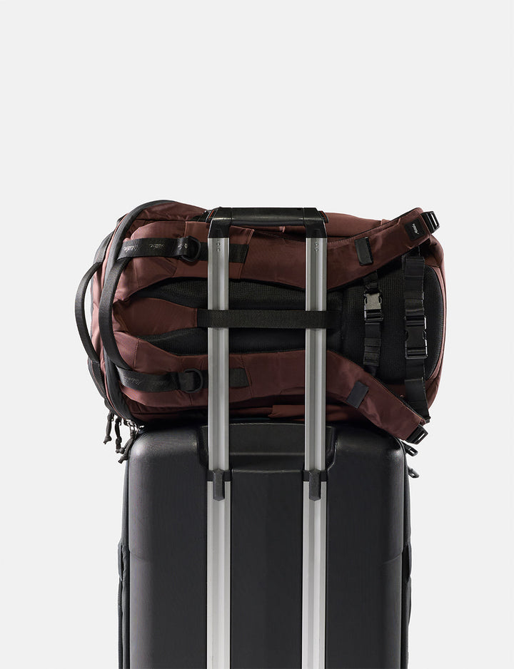 Matador 24L Adventure Pack in Garnet - garnet backpack sitting on black suitcase