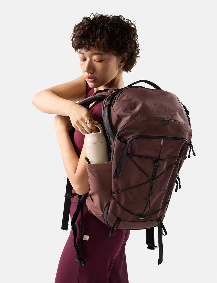 Matador 24L Adventure Pack in Garnet - person pulling a water bottle out of garnet backpack