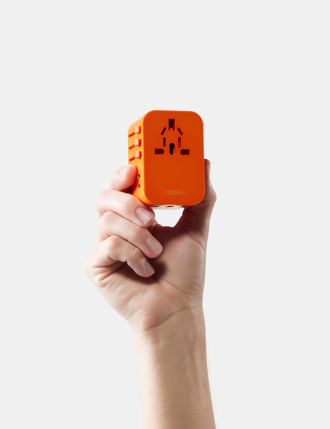 Matador Global Travel Adapter in Orange - hand holding an orange travel adapter against a white background