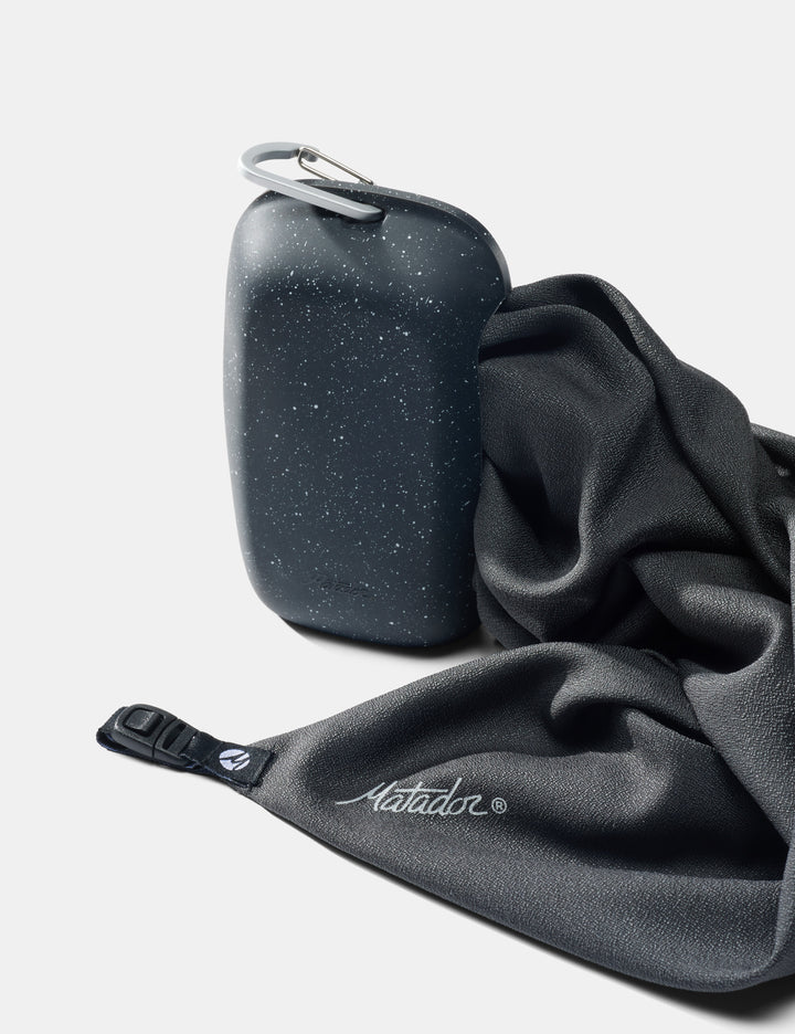 Matador NanoDry Towel - Large 132 x 60cm in Black Granite - nanodry towel being pulled out of silicone case on white background