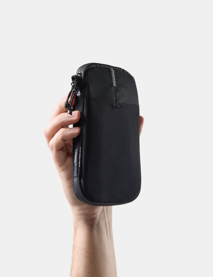 Matador Global Travel Stash in Black - hand holding closed travel wallet on white background