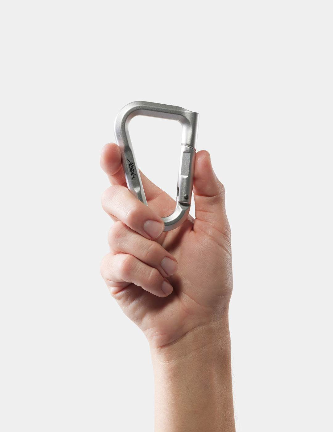 Matador BetaLock in Metal - hand holding a metallic carabiner against a white background