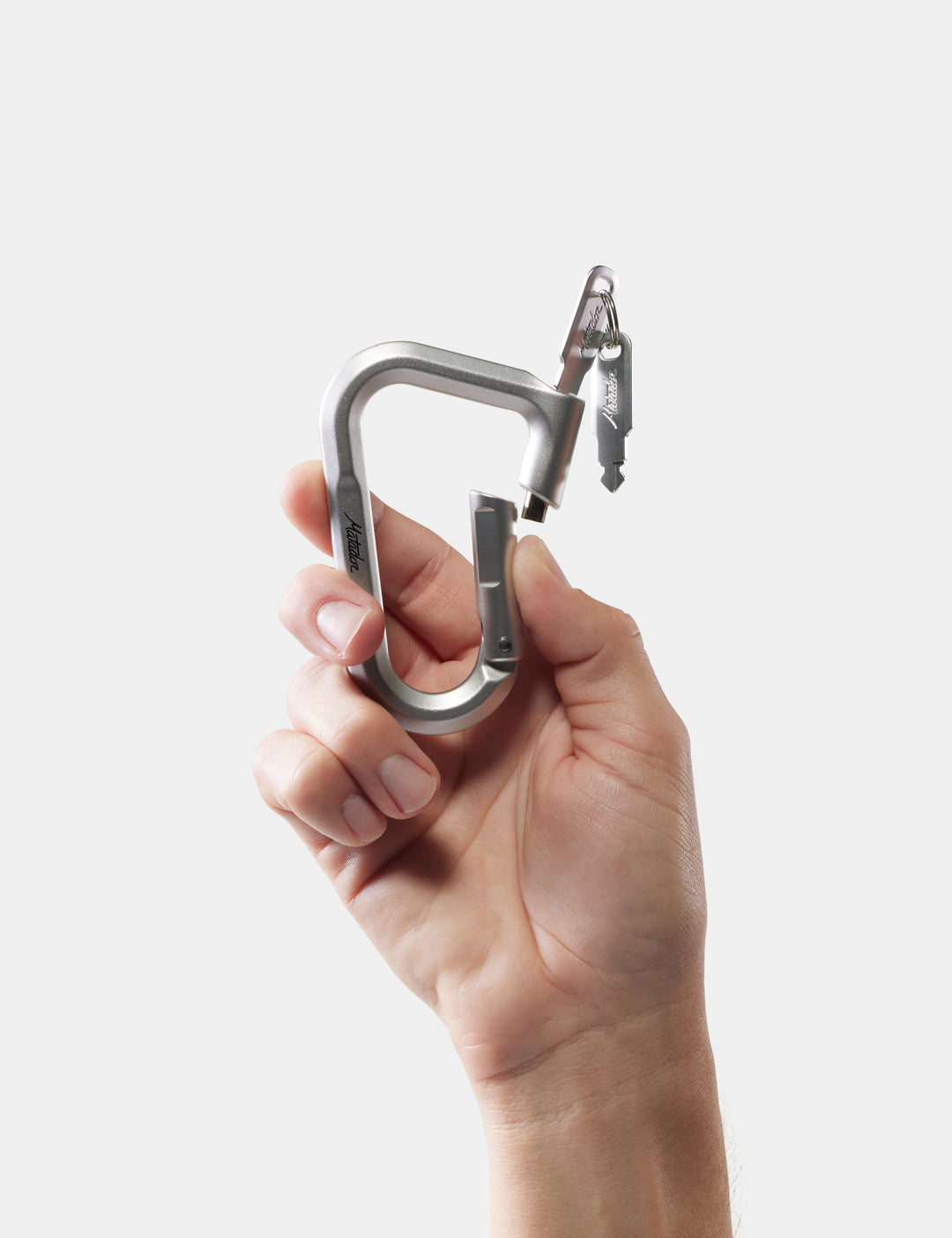 Matador BetaLock in Gold - hand holding a metal carabiner against a white background