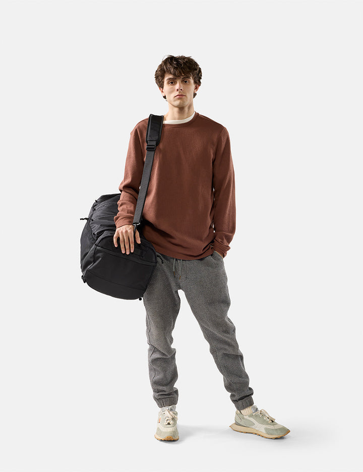 Matador 45L SEG Hybrid Travel Pack in Black - man holding a black duffel bag against a white background