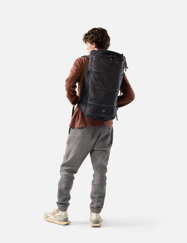Matador 45L SEG Hybrid Travel Pack in Black - person wearing a black backpack on a white background