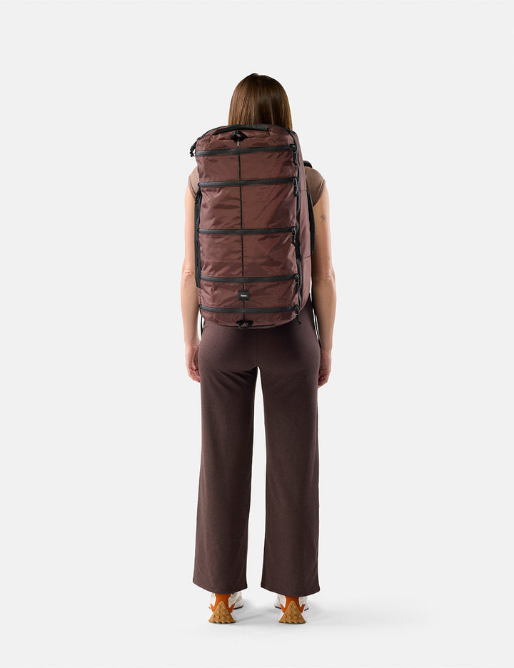 Matador 45L SEG Hybrid Travel Pack in Garnet - person wearing a large Garnet backpack on a white background