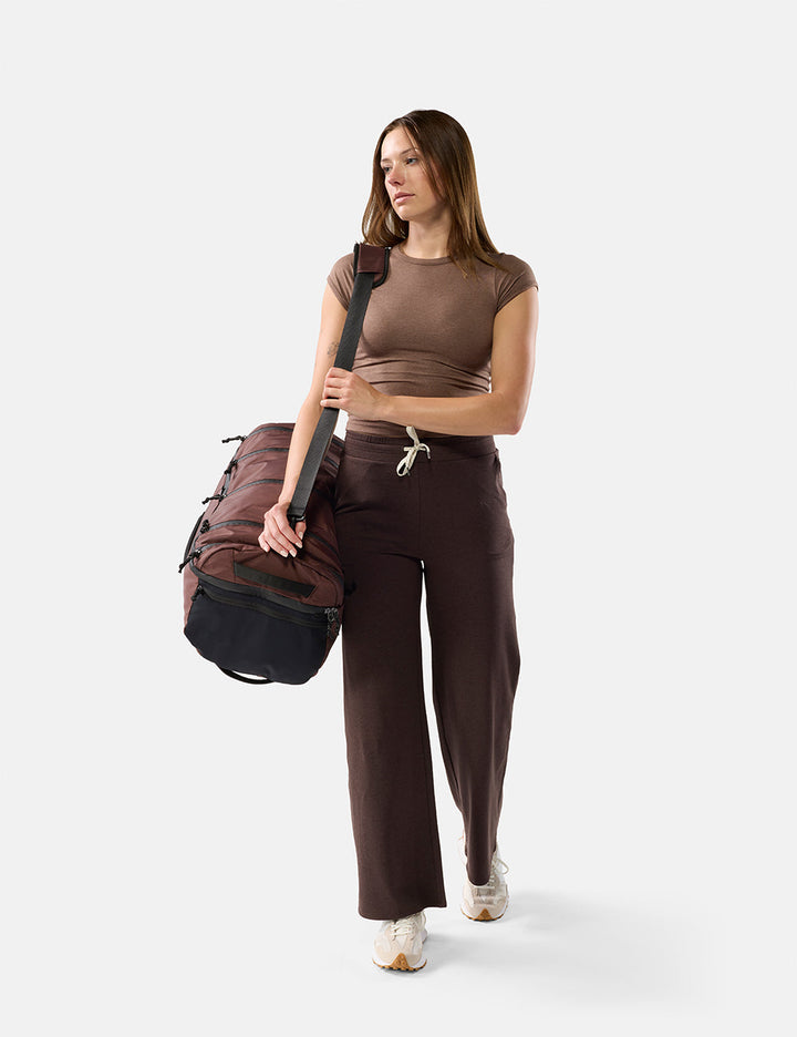 Matador 45L SEG Hybrid Travel Pack in Garnet - woman holding a duffel bag against a white background