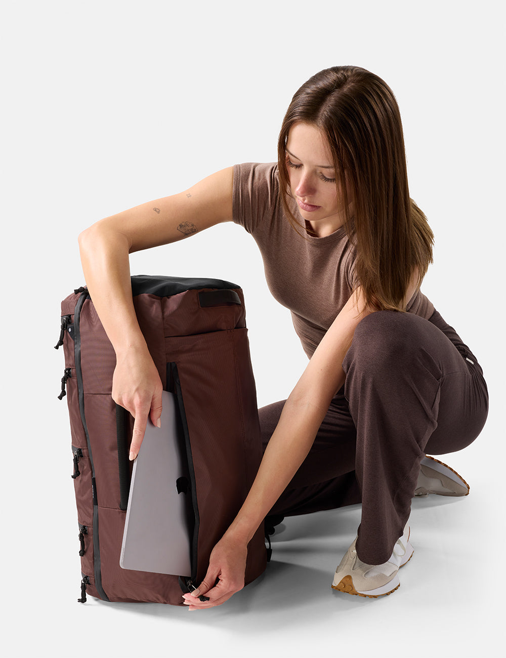 Matador 45L SEG Hybrid Travel Pack in Garnet - woman organizing a large Garnet backpack on a white background