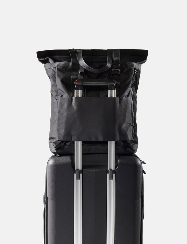 Matador 24L Tote Pack in Black - black tote pack on top of a suitcase with a white background