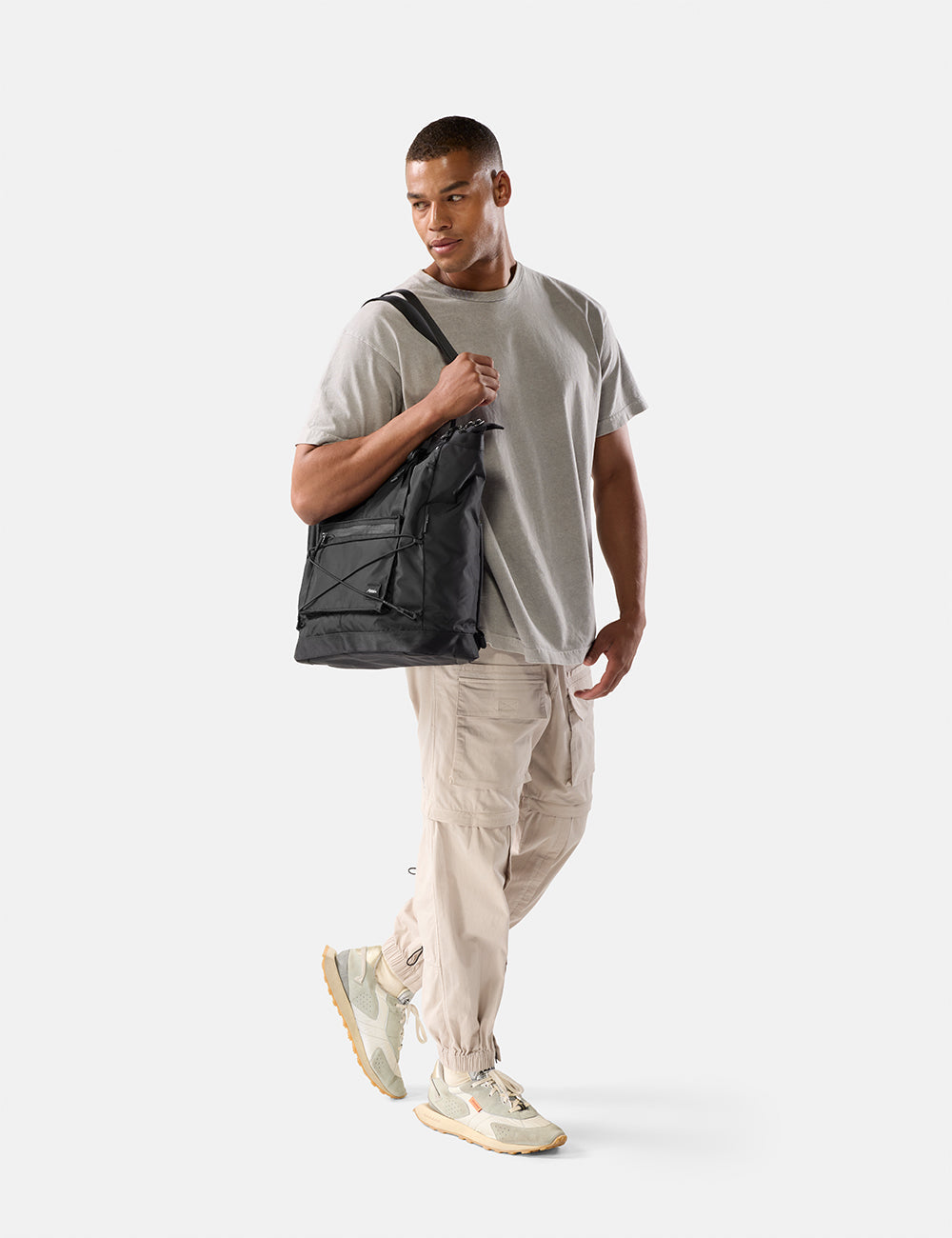 Matador 24L Tote Pack in Black - man holding a black tote pack against a white background