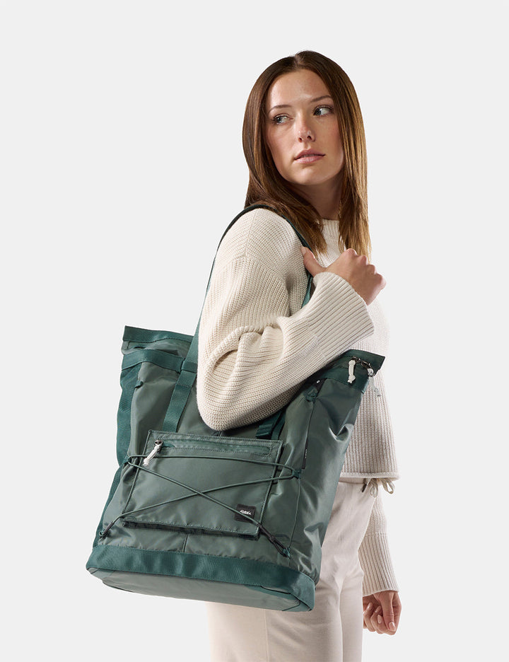 Matador 24L Tote Pack in Juniper - woman on white background wearing green tote over her shoulder