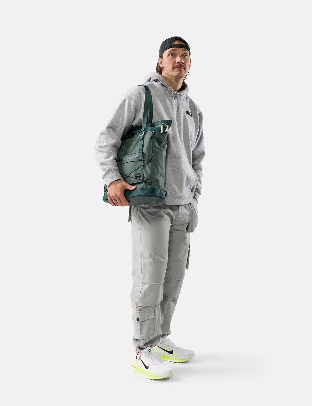 Matador 24L Tote Pack in Juniper - person wearing a gray outfit with a green tote pack on a white background