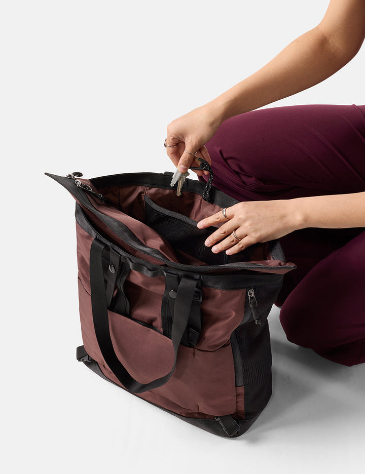 Matador 24L Tote Pack in Garnet - person opening a maroon and black bag on a white background