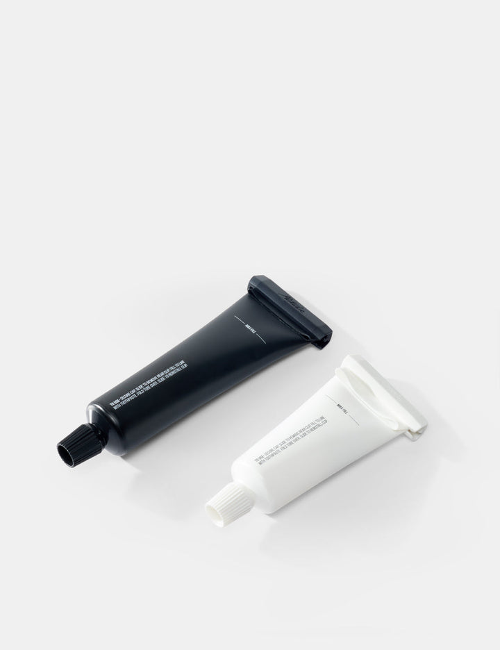 Matador Refillable Toothpaste Tubes - 2 Pack - two tubes , one black and one white, on a light gray background