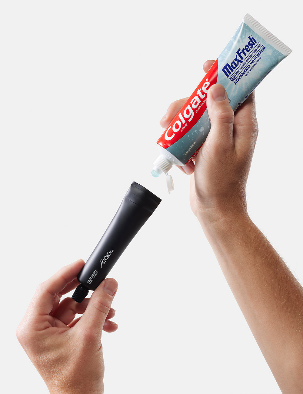 Matador Refillable Toothpaste Tubes - 2 Pack - colgate MaxFresh toothpaste tube being squeezed onto a black applicator against a white background